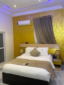 ein Schlafzimmer mit einem großen Bett und einer gelben Wand in der Unterkunft Providha Hotel & Suites in Ikeja