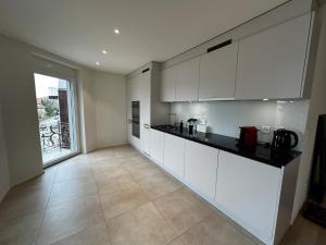 a kitchen with white cabinets and a large window at Seeblick Wohnung in Wollishofen in Zurich +4 photos