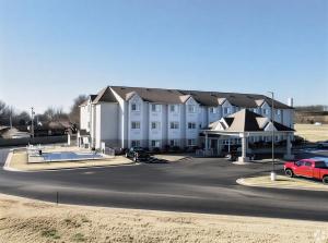 a large white building with a red car in front of it at Microtel Inn & Suites Claremore Route 66 in Claremore