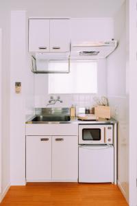a white kitchen with a sink and a microwave at Chic Nakasu Apartment Perfect for 2 Guests in Fukuoka +47 photos