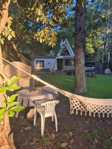 a hammock and a table and chairs under a tree at Estrellita Mia in Villa Ciudad Parque