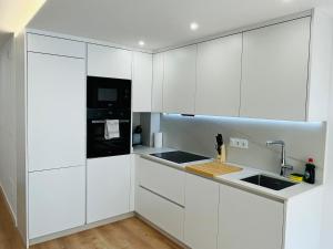 a white kitchen with white cabinets and a sink at RÍA LIVING - Arena 01 in Cee