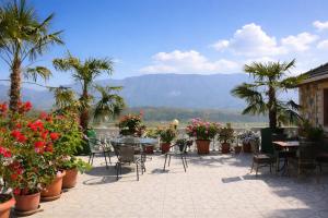 a patio with tables and chairs and palm trees and flowers at Guest house Memushi in Gjirokastër