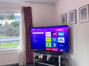 a flat screen tv sitting on a stand next to a window at River house in Birnam