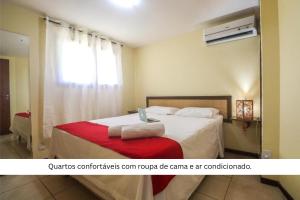 a bedroom with a bed with a red blanket and a window at Solar Pipa by Pipa Centro in Pipa