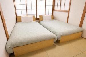 two beds in a small room with windows at Sakura Hotel Hatagaya in Tokyo