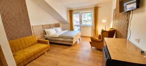 a bedroom with a bed and a couch and a window at „Amber” Pokoje z widokiem na morze in Krynica Morska