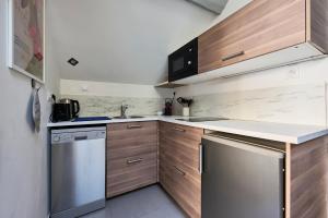 a small kitchen with wooden cabinets and a dishwasher at Le Bossuet - Cosy et Charme au Centre Historique in Dijon