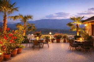 a patio with tables and chairs and palm trees at Guest house Memushi in Gjirokastër