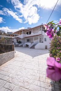 a large white house with a courtyard with purple flowers at Velora Apartments Ksamil in Ksamil