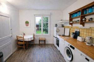 a kitchen with a table and a white refrigerator at Gîte Le Repos de Merlin - Paimpont, Forêt de Brocéliande in Paimpont