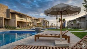an umbrella and a bench next to a swimming pool at Boho sokhna families only in Ain Sokhna