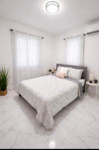 a white bedroom with a large bed with white curtains at La Casita del Este in Fajardo