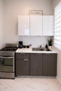 a kitchen with white cabinets and a stove and a sink at La Casita del Este in Fajardo +11 photos
