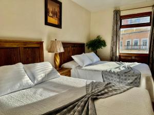 a hotel room with two beds and a window at San Carlo hotel in Guanajuato