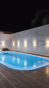 a blue swimming pool in front of a wall at night at Área de Lazer BR 267 in Bataguaçu