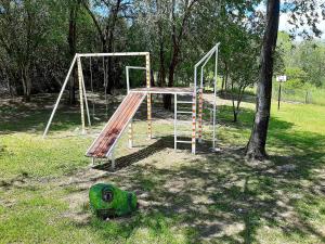 a swing set in a park next to a tree at Cabañas Tinku del Sol in Casa Grande
