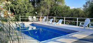 a swimming pool with white chairs and tables and a fence at Cabañas Tinku del Sol in Casa Grande