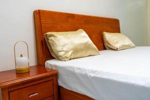a bed with a wooden headboard next to a night stand at Résidence Madior D1 in Dakar +1 photo