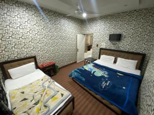 a bedroom with two beds and a tv on a wall at Getaway lodge Guesthouse in Islamabad