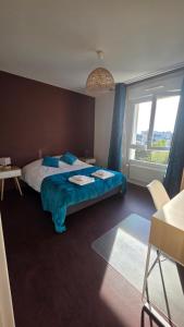 a bedroom with a bed with blue sheets and a window at Le haie vigné in Caen
