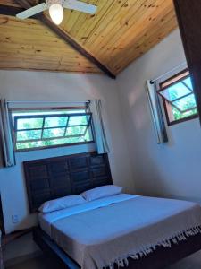a bedroom with a bed and two windows at Cozy, rustic apartment with balcony in Búzios