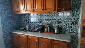 a kitchen with wooden cabinets and blue tiles on the wall at Maison Mira in Bizerte
