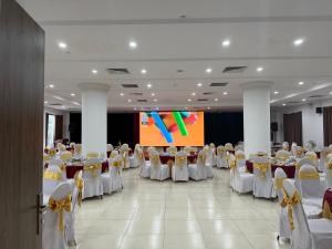 a banquet hall with white tables and chairs and a screen at Nhà khách Bông Sen in Vinh