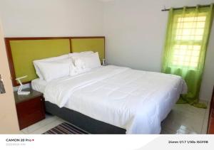 a bedroom with a large bed with white sheets at Raneziah Guesthouse in Kasane