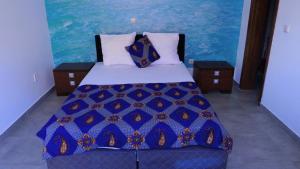 a bedroom with a bed with a blue comforter at Appartement dépaysante T1B in Tarrafal