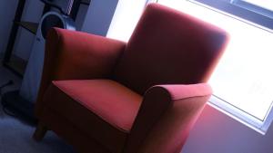 a red chair sitting in front of a window at Appartement dépaysante T1B in Tarrafal