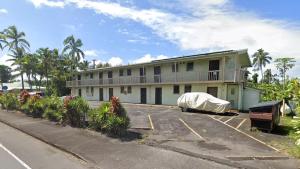 a white building with a balcony and a parking lot at Oceanfront Views • Balcony + Top Hilo Location in Hilo