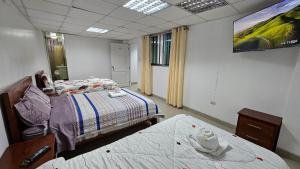 Ein Zimmer mit zwei Betten und einem Fernseher an der Wand. in der Unterkunft Hostal Ticlio in Cajamarca + 2 Fotos