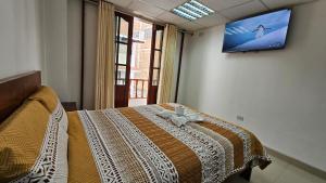ein Schlafzimmer mit einem Bett und einem Fernseher an der Wand in der Unterkunft Hostal Ticlio in Cajamarca