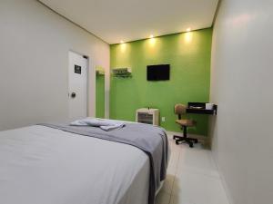 a bedroom with a bed and a green wall at Villa Hospedagem in Palmas