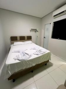 a bedroom with a bed with white sheets and a window at Villa Hospedagem in Palmas