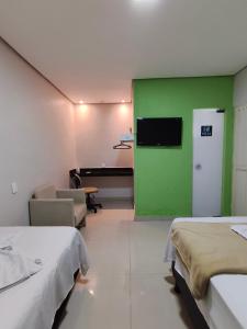 a room with two beds and a green wall at Villa Hospedagem in Palmas +8 photos
