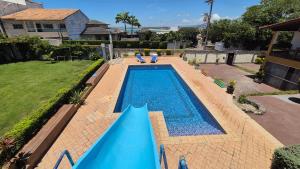 a swimming pool with a blue slide in a yard at Hostel-Casa25-Meaipe in Guarapari +14 photos