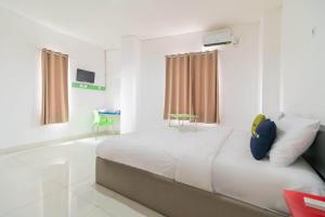 a white room with a bed and a green chair at Urbanview Hotel Ephe Palembang by RedDoorz in Palembang