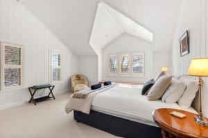 a white bedroom with a large bed and a table at Mulgrave House & Cottage in Bellawongarah