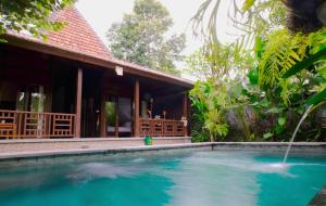 a swimming pool in front of a house at Prama House in Ubud
