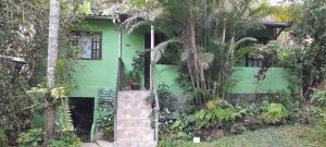 a green house with a palm tree in front of it at Cantinho do Rio in Penedo