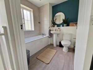a bathroom with a tub and a toilet and a sink at Gatwick Cozy Stopover 4 bedroom house with free Parking in Copthorne