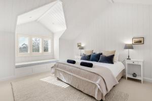 a white bedroom with a large bed and a window at Mulgrave House in Bellawongarah