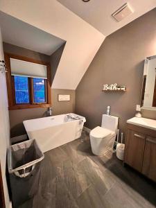 a bathroom with a tub and a toilet and a sink at Manoir Signature in Mont-Tremblant