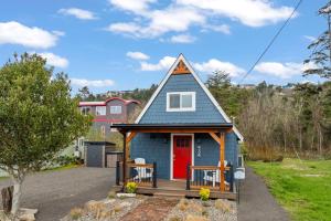 a small blue house with a red door at Cozy Coastal Cabin in Rockaway Beach