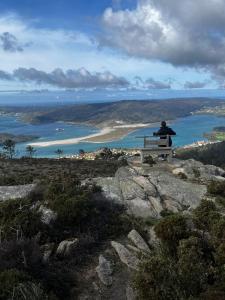 a man sitting on a bench on top of a hill at Corme camiño dos faros, playa Galicia in Corme-Puerto