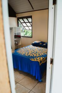 a bedroom with a bed with blue sheets and a window at FAKARAVA - Teariki Lodge 1 in Fakarava