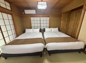 two beds in a small room with windows at HoTTOSTAY矢田 in Nagoya