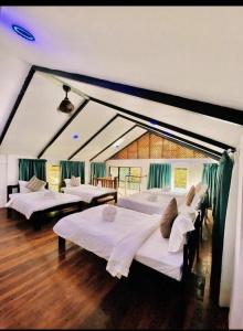 a room with four beds in it with green curtains at Bidaisari Resort in Kampong Sum Sum